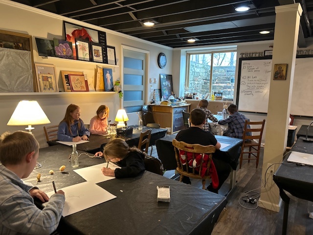 Instructor helping a student with an artwork at the studio table