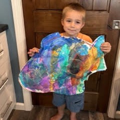 Student holding a colorful panel of heart paintings
